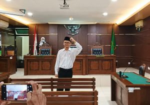 Terdakwa Perdana Arie mengepalkan tangannya dalam sesi dokumentasi sebelum dibukanya Sidang Pembacaan Pleidoi pada Rabu (18/2/2026) di PN Sleman. Foto oleh Luisa/EKSPRESI.